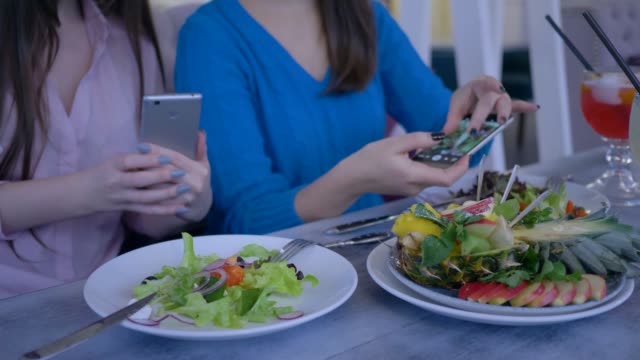 Händen-der-Frauen-Freunde-mit-Handy-für-Foto-des-schönen-Salat-während-gesundes-Abendessen-während-Diät-zur-Gewichtsreduktion-in-restaurant