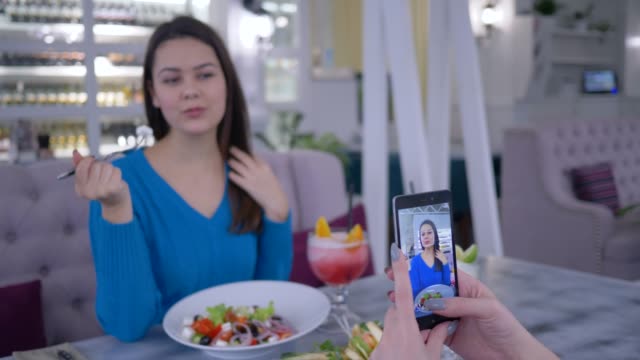Portrait-von-vegetarischen-Frau-mit-frischen-nützlich-Salat-in-der-Hand-fotografiert-auf-Handy-für-soziale-Medien-während-des-Mittagessens-im-restaurant