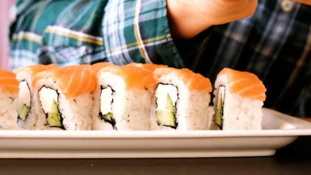 Man-eats-rolls-with-chopsticks-in-a-restaurant-close-up