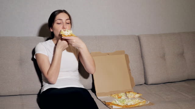 Glückliches-Mädchen-in-Essen-Pizza-zu-Hause