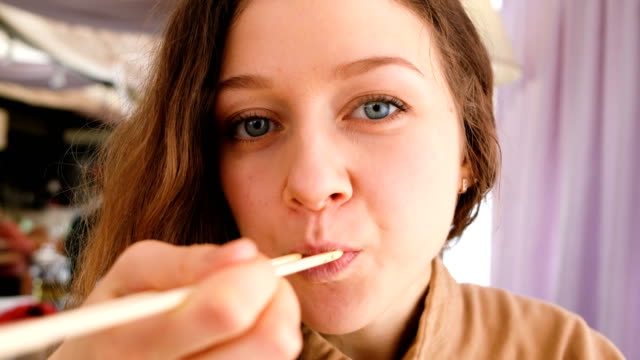 Young-beautiful-girl-with-blue-eyes-eating-salad-sticks-in-a-cafe-restaurant