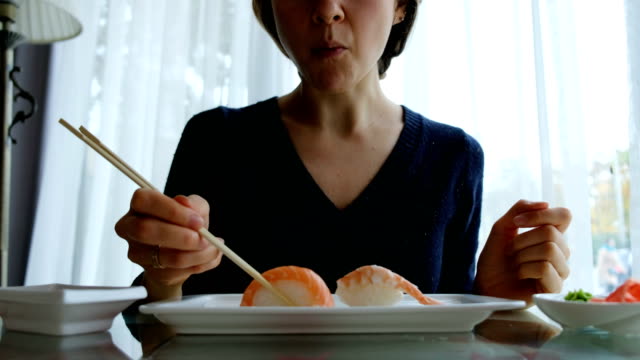 joven-caucásica-comer-sushi-en-restaurante-japonés