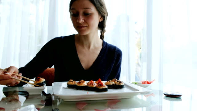 joven-caucásica-comer-sushi-en-un-restaurante-japonés