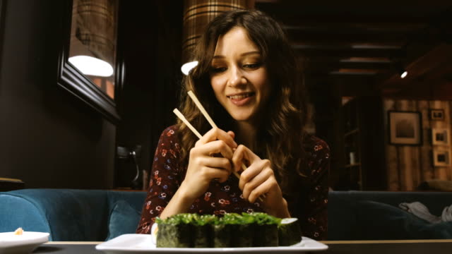 Schöne-Frau-kaukasischen-Essen-Sushi-in-ein-japanisches-Restaurant-und-etwas-interessantes-erzählt-seiner-Freundin-gegenüber