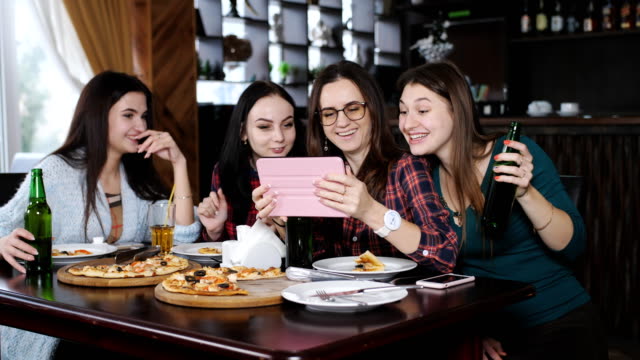 Die-Gesellschaft-von-Freunden-in-einem-Restaurant-mit-Pizza-und-Bier,-Spaß,-Austausch-und-Anzeigen-von-Fotos-auf-dem-Tablet.