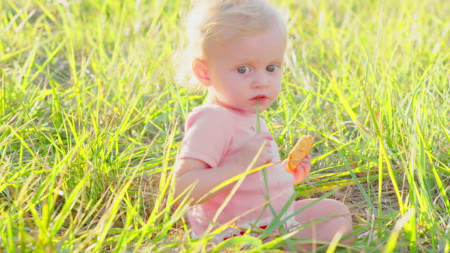 Cute-blonde-Kleinkind-draußen-in-der-Sonne-mit-cracker
