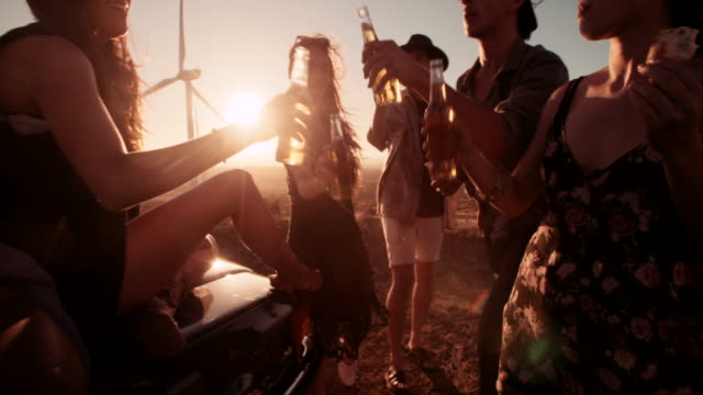 Boho-Friends-toasting-at-sunset-with-beer-and-pizza