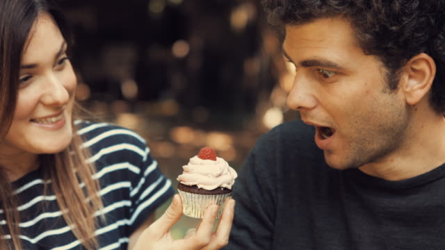 Junges-Mädchen-bietet-eine-süße-Himbeere-Cupcake-zu-Ihrem-Freund