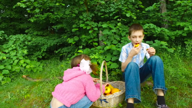 Los-niños-tienen-un-descanso-en-el-bosque.-Cena-en-el-bosque-frutas.-Chico-adolescente-comer-damasco.