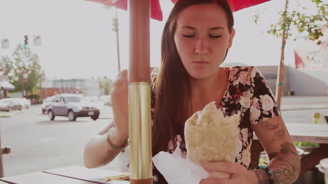Ein-Schönes-Mädchen-ein-einem-Tisch-im-Freien-essen-ein-Burritos,-Zeitlupe