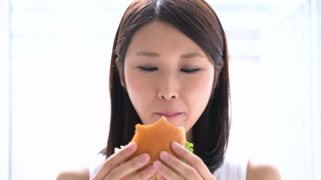 mujer-joven-comer-hamburguesa