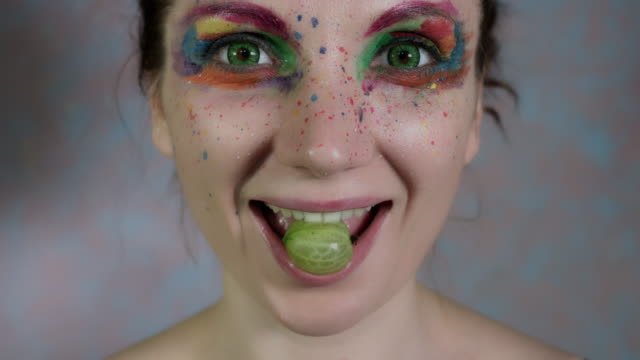 4-k-Aufnahme-einer-Frau-mit-bunten-Make-up-Essen-Stachelbeere