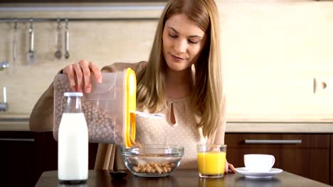 Beautiful-young-attractive-woman-pouring-cornflakes-in-a-bowl-for-breakfast-in-the-kitchen