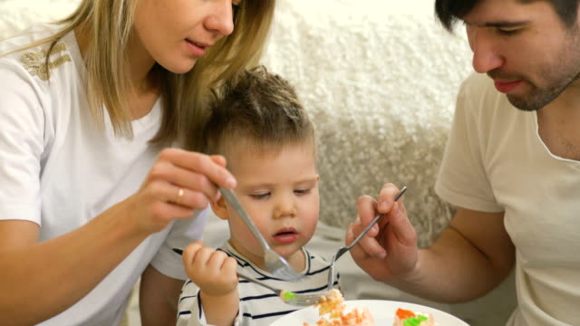 Kleine-entzückende-Junge-feiert-seinen-Geburtstag-fütterung-seinen-Vater-und-Mutter-mit-Kuchen