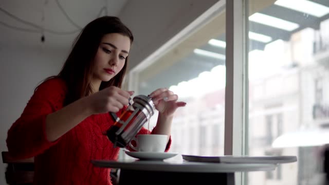 Frau-macht-Französisch-drücken-Tee-beim-Frühstück.-Glücklich-lächelnde-Mädchen-Tee-im-Café-trinken.-Kaukasische-weibliches-Modell.