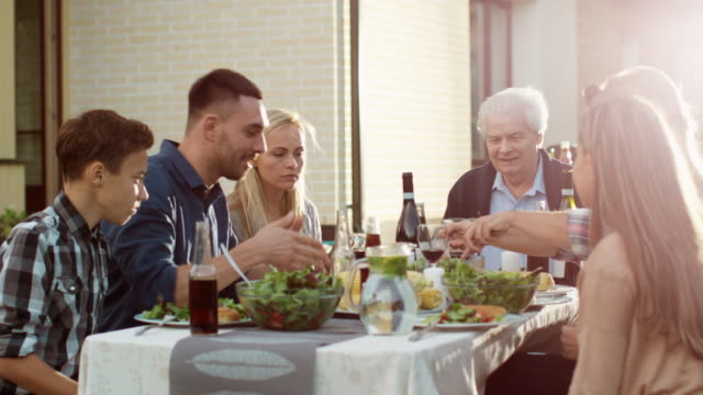 Group-of-Mixed-Race-People-Having-fun,-Communicating-and-Eating-at-Outdoor-Family-Dinner