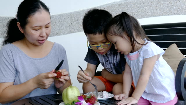 Children-and-mother-eating-fruits-on-table