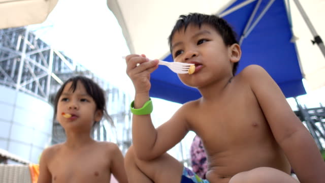 Asiatische-Kind-isst-Pommes-Frites-am-Strand