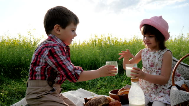 girl-and-Boy-with-food-on-nature,-Happy-children-in-fresh-air,-Bread-and-dairy-products-eating,-during-rest,-Holiday-in-nature