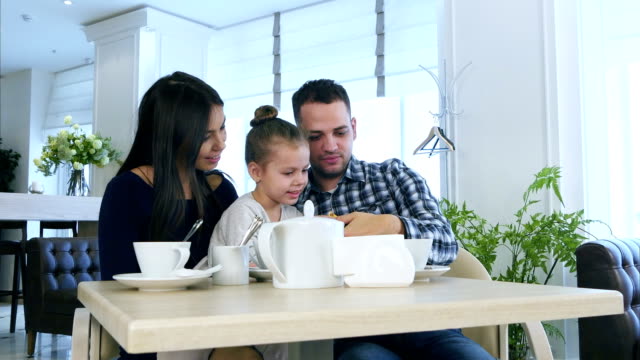 Glückliche-junge-Familie-Blick-auf-Smartphone,-zu-diskutieren-und-zu-Lächeln