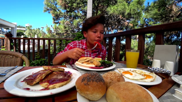 Preteen-boy-eating-breakfast-at-the-outdoor