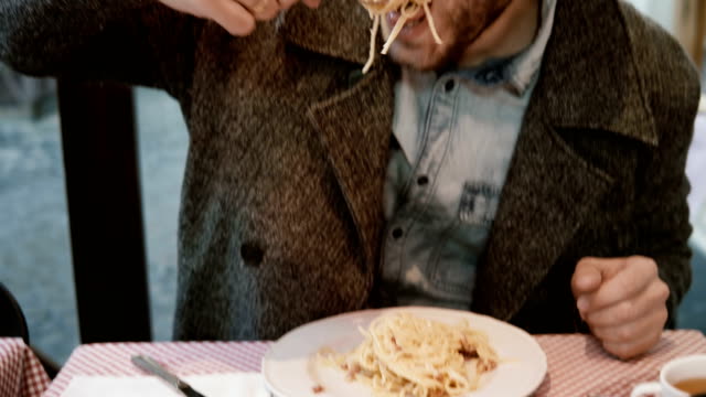 Hübscher-junger-Mann-am-Tisch-im-Café-sitzen-und-genießen-das-Essen.-Hungrige-männlich-leckere-Pasta-im-Restaurant-Essen