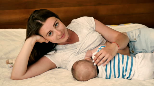 Portrait-of-young-mother-breastfeeding-her-baby-at-the-bed