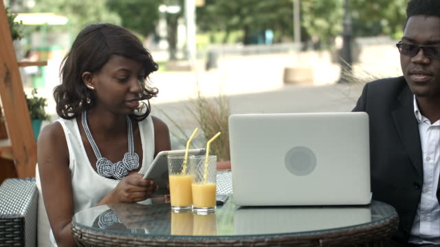 Afro-American-Business-Mann-und-Frau-zusammen-in-modernen-Café-arbeiten,-telefonieren,-mittels-Laptop-und-digital-Tablette
