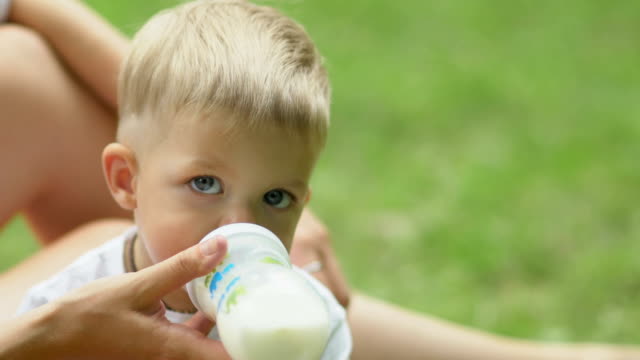 Kleiner-Junge-trinkt-Milch-aus-Babyflasche