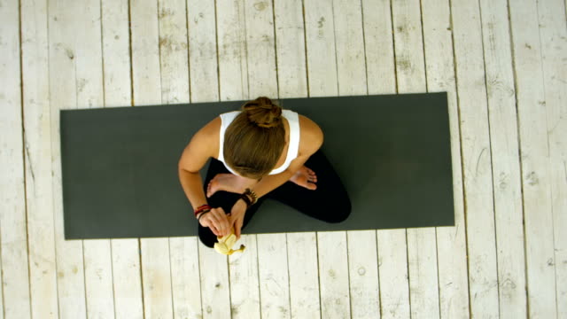 Mujer-joven-comer-plátano-después-de-clase-de-yoga