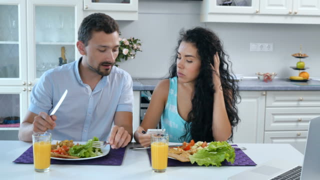 Frau-zeigt-etwas-auf-Smartphone-Mann-während-des-Frühstücks-in-Küche