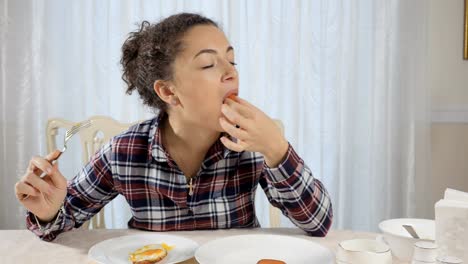 Woman-eats-scrambled-eggs-and-sausage-with-appetite