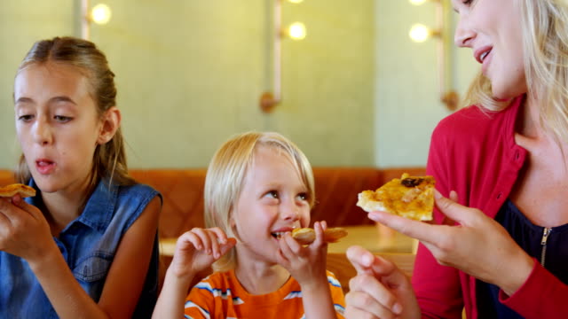 Madre-y-niños-pizza-en-restaurante-4k