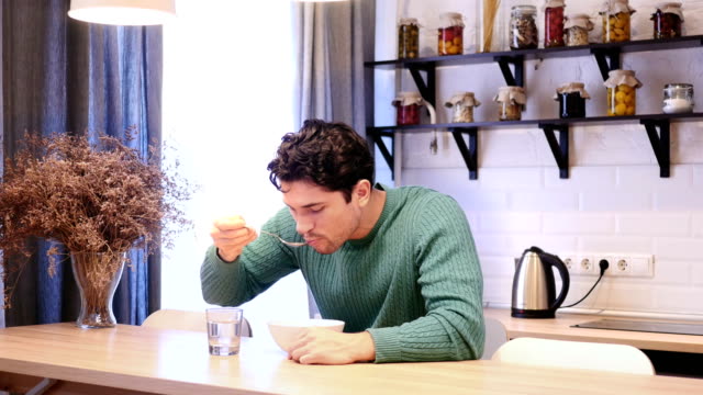 Young-Man-Eating-Food-in-Kitchen
