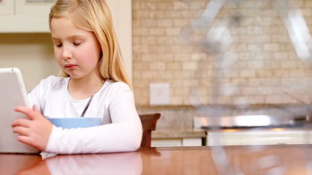 Little-girl-using-tablet-while-having-breakfast-4K-4k
