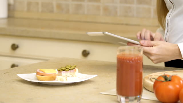 Mädchen-isst-Sandwich-und-Tablet-stehen-in-der-Küche-verwendet