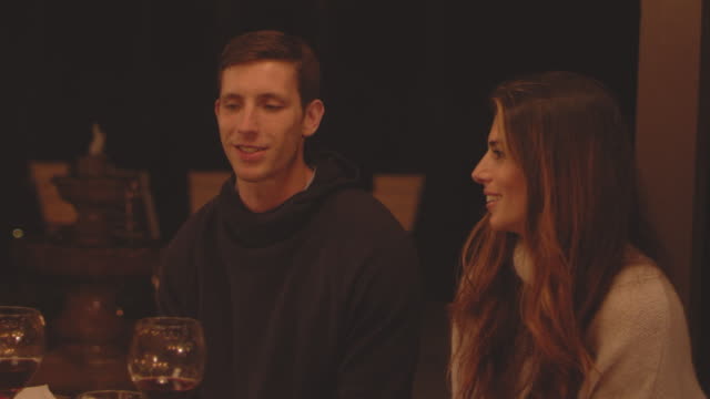 Young-loving-couple-talking-and-laughing-at-a-dinner-table