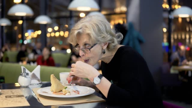 Eine-Frau-mittleren-Alters-frisst-Dessert-in-einem-Café.