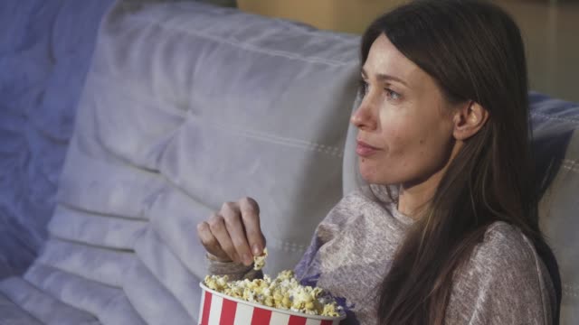 Close-up-of-a-mature-woman-eating-popcorn-smiling-at-the-cinema