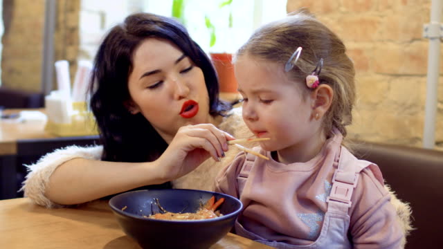 Junge-koreanische-füttert-ihre-kleine-Tochter-mit-Nudeln-im-restaurant