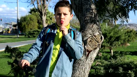 Young-boy-licking-a-lollipop-at-the-outdoors