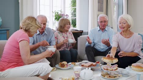 Gruppe-von-Senioren-Freunde-Afternoon-Tea-zu-Hause-gemeinsam-genießen