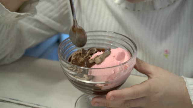 Das-kleine-Mädchen-mischt-sich-Schokolade-und-Erdbeer-Eis-in-eine-Tasse.