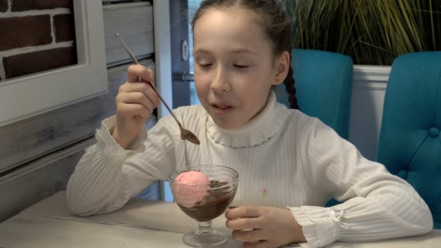Ein-kleines-Mädchen-mit-Sommersprossen-im-Gesicht-in-einem-Café-sitzen-und-Eis-essen.