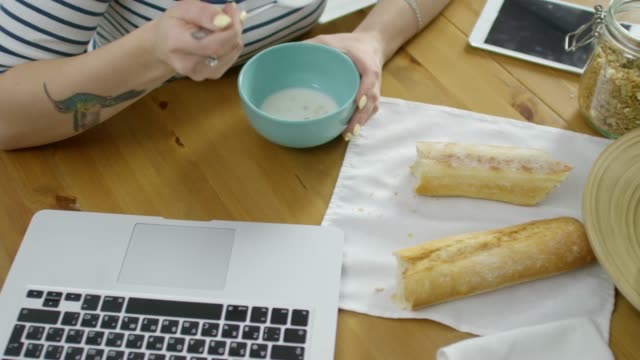 Mujer-que-trabaja-en-la-computadora-portátil-mientras-desayuno-comer