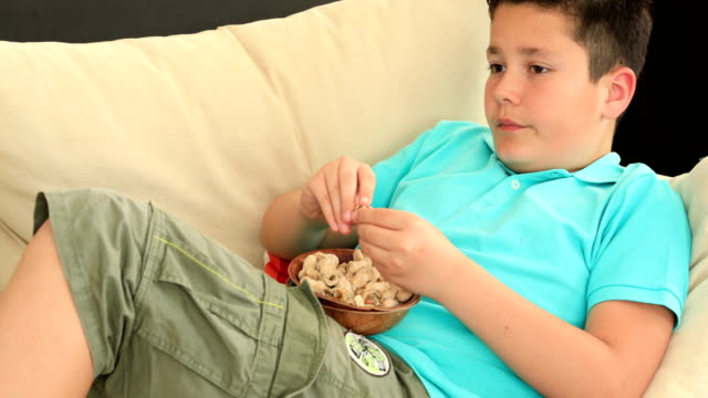 Kleiner-Junge-Erdnüsse-zu-essen-und-vor-dem-Fernseher