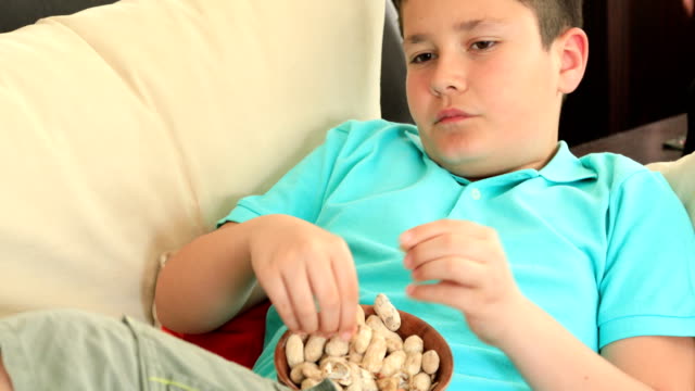 Young-boy-eating-peanut-and-watching-tv