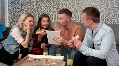 Gruppe-von-Freunden-essen-Pizza-zum-Mitnehmen-und-Programm-auf-Tablet-ansehen