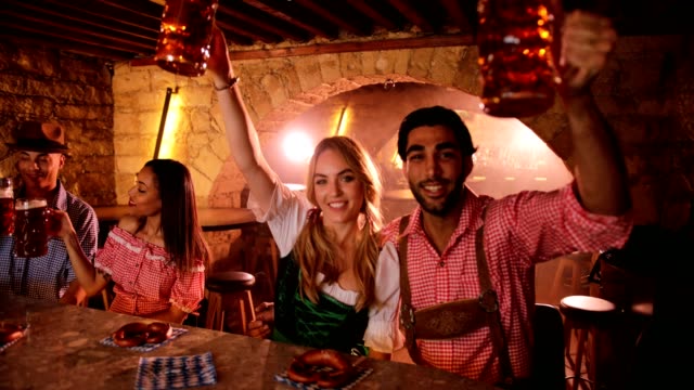 Young-couple-celebrating-Oktoberfest-with-beer-and-pretzels-at-bar