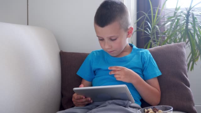 Junge-im-Mittelpunkt-Screen-Tablette-beim-sitzen-alleine-im-Zimmer